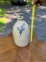 Stoneware jug with hand-painted cobalt blue floral motif, shown with tape measure indicating height approximately 11 inches.