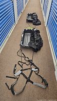 Overhead view of two black plastic sleds with harnesses and ropes laid out in a hallway.