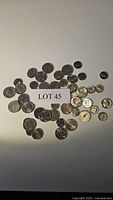Photo of assorted coins spread on white surface including U.S., Canadian, and EU coins with lot label 45