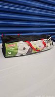 Coleman branded black carry bag with red straps, labeled for 6-person tent, showing tent dimensions.