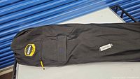 Black carry bag laid flat on table, Frabill logo patch and zippered pocket visible