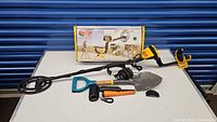 Metal detector assembled on table with box in background, shovel, headphones and pinpointers laid out