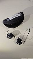 Head-mounted magnifying glasses with dual lenses, adjustable frame, LED light, and carrying case included.