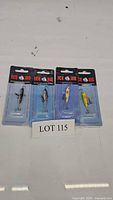 Four new and sealed Ice Jig fishing lures in original blister pack packaging arranged in a row with variety of patterns and colors for ice fishing.