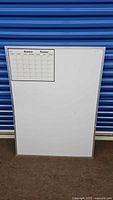 Front view of large dry erase whiteboard with monthly planner grid in upper left corner, full visible lower area for notes, metallic frame visible at edges.