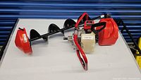 Overall view of Rapala Vortex ice auger with engine, frame, fuel tank, and 8-inch auger bit on table.