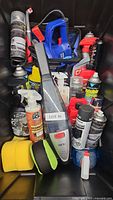 Simoniz blue 8-inch random orbit polisher among spray bottles, handheld vacuum, microfiber sponges, and spray cleaners inside a container