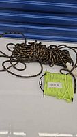 Overall view of two coiled utility ropes placed on a white surface against a blue background - one camo pattern and one neon yellow.