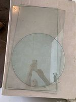Three glass panels on flat surface, two rectangular and one round on top.