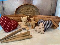 Wide view showing the two rectangular Longaberger baskets, oval basket, three Americana-themed fabric hearts, two Attic Babies teddy bears, and four wooden spindles arranged on table.