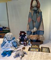 Full view of the lot showing all rag dolls, printed art, and wooden figures on a white table against a neutral background.