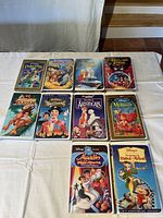 Full view of 11 Disney VHS movies arranged on table with original clamshell cases, showing colorful illustrated covers