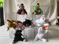 Full view of all Beanie Babies included in lot along with display cases, showing Spangle bear, Nip cat, Garcia bear, Flip cat with Baby Flip, and Zip cat with Baby Zip mini Beanies.