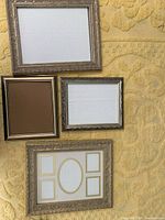 Four decorative gilded frames displayed together on a textured yellow surface showing different sizes and styles including one collage-style frame with multiple openings.