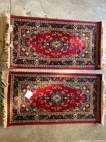 Photo showing two matching burgundy Persian-style throw rugs laid flat, highlighting overall design and size.