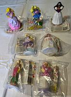 Set of 7 Barbie Princess figurines mostly sealed in original packaging with some unsealed figurines visible.