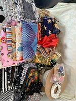 Various colorful and kid-themed novelty fabric pieces stacked with black and white fabrics and sewing supplies such as welt cord and thread basket on the side