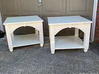 Photo of two off-white indoor end tables side by side on a driveway in front of a garage door, showing front and side angles