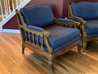 Pair of wood-framed chairs with blue upholstery viewed from the side showing chair design and wood detail.