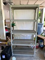 Front view of the full plastic garage shelving unit showing all five shelves and frame