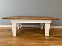 Full side view of the coffee table showing white legs and natural distressed wood top