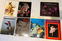 Seven mint commemorative stamp set albums from years 1987-1998. Covers show wildlife, musical icons, marine life, flowers, and ballet themes.