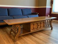 Side angle photo showing sturdy wood construction, decorative legs, and cabinet door detail with metal hinges.