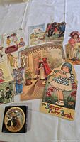 Overview photo showing several vintage style children's books, postcards, and the Barbie ornament box on a white surface.