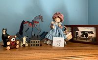 Overview of lot showing vintage doll, wooden rocking horse, teddy bear, miniature house with water wheel, farm art prints, and small animal figurines.