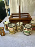 Wooden basket with a handle and five vintage labeled food cans arranged in front