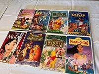 Photo showing eight Walt Disney VHS tapes in clamshell cases, including Mulan, Lady and the Tramp, Pocahontas, Winnie the Pooh, The Three Caballeros, Oliver & Company and Toy Story.