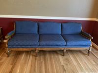 Frontal view of the three-seater wood framed sofa with navy blue upholstery showing the seat cushions and carved wood base.