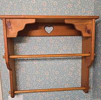 Front view of wooden towel rack showing two dowels for towels and heart cutout detail on back panel