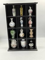 All 12 miniature vases arranged in black wood cubby display stand