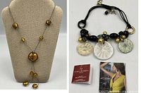 Both necklaces displayed: amber lariat on bust, multicolor bib choker with literature