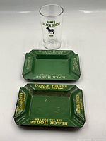 Front view of two ashtrays and glass showing logos and condition