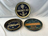 Front view of three vintage beer trays: Molson’s Ale, O’Keefe’s Old Stock Ale, Standard Ale