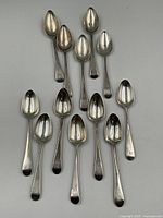 All 12 sterling silver spoons laid flat showing size difference