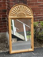 Full view of mirror leaning against brick wall