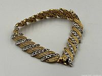 Bracelet in triangular arrangement showing gold-tone textured and crystal-set links