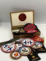 overview of cigar box with multiple embroidered patches, cap badge, shoulder titles