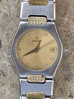 Close view of dial showing brand, diamonds, date window and two-tone bezel