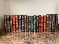 All 20 leather-bound books lined up, showing varying spine colours and gilt tooling