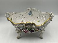 Front view showing pierced sides, handles, gilt accents, applied flowers
