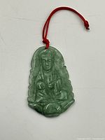 Front view of green carved pendant with red cord