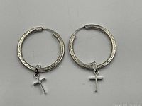 Front view of sterling silver hoop earrings with dangling crosses