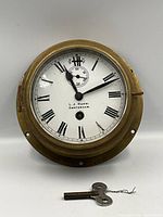 Front view of brass ship's clock with key