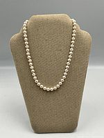 Pearl necklace displayed on fabric bust stand