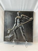 Full view of square metal relief plaque on stand