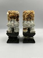 Front view of both guardian lions showing male with ball and female with cub